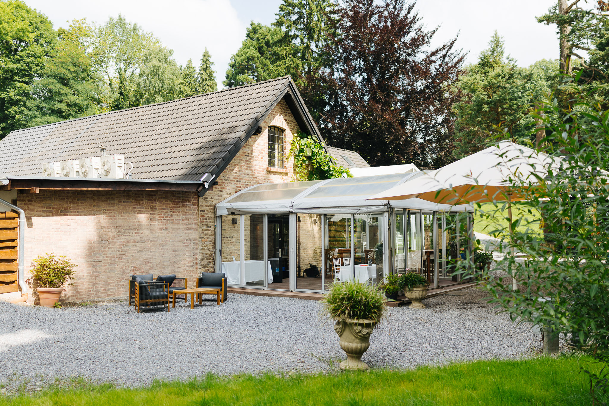 Wintergarten und Außenbereich der Hochzeitslocation Schloss Grünewald in Solingen mit Sitzgelegenheiten im Grünen.